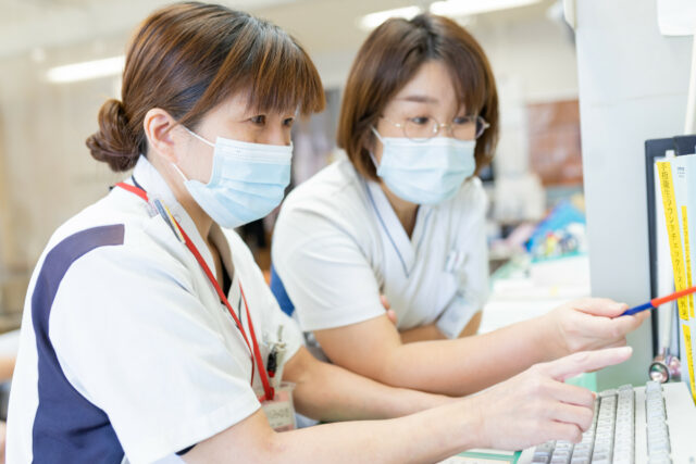 写真：パソコン画面を見る看護師